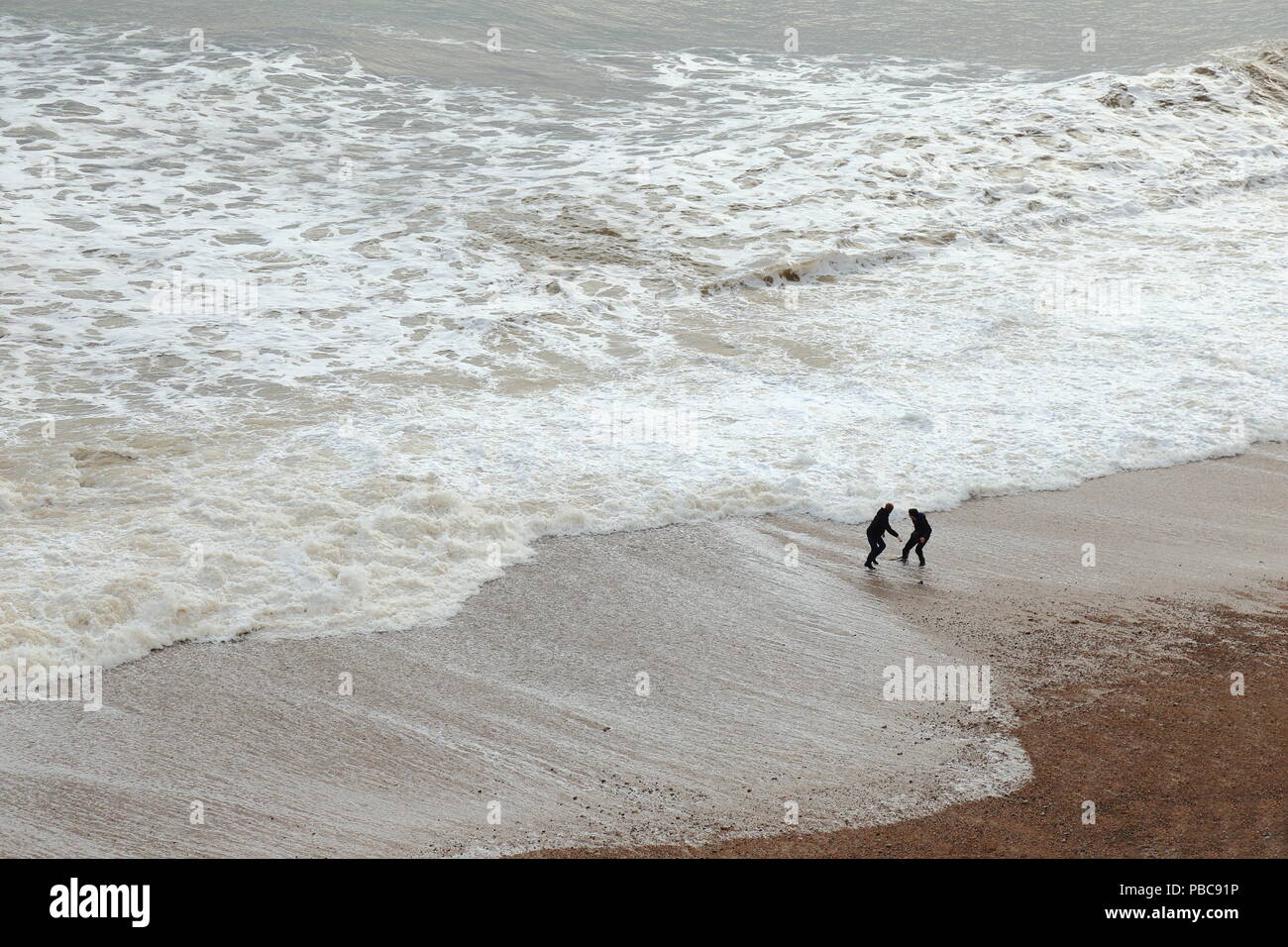 Les gens s'amusant avec des vagues sur la côte jurassique Banque D'Images