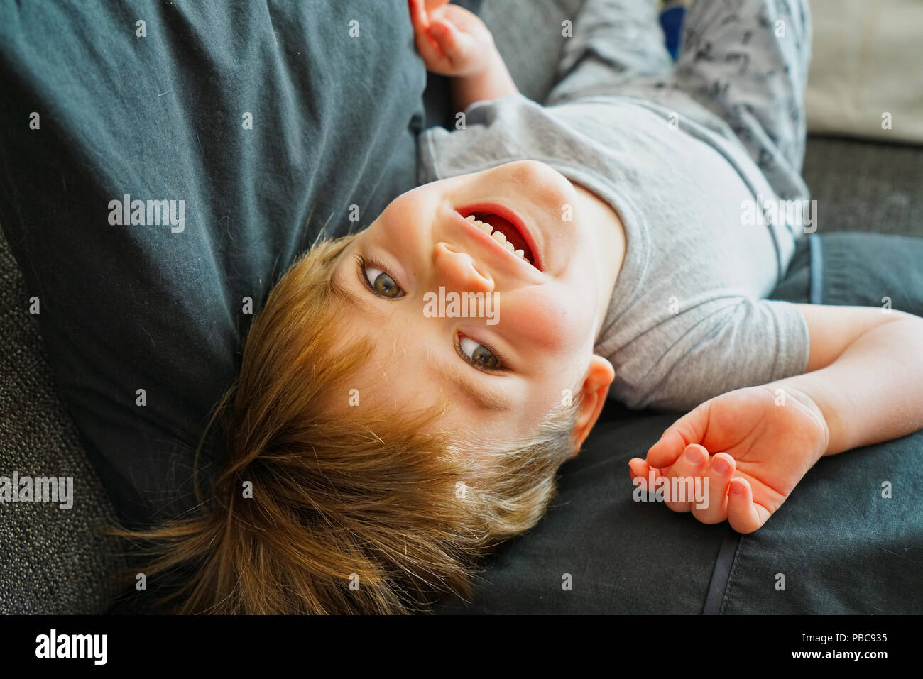 Montréal,Canada,21,juillet 2018.Jeune garçon riant à l'envers sur le canapé du salon.Credit:Mario Beauregard Banque D'Images