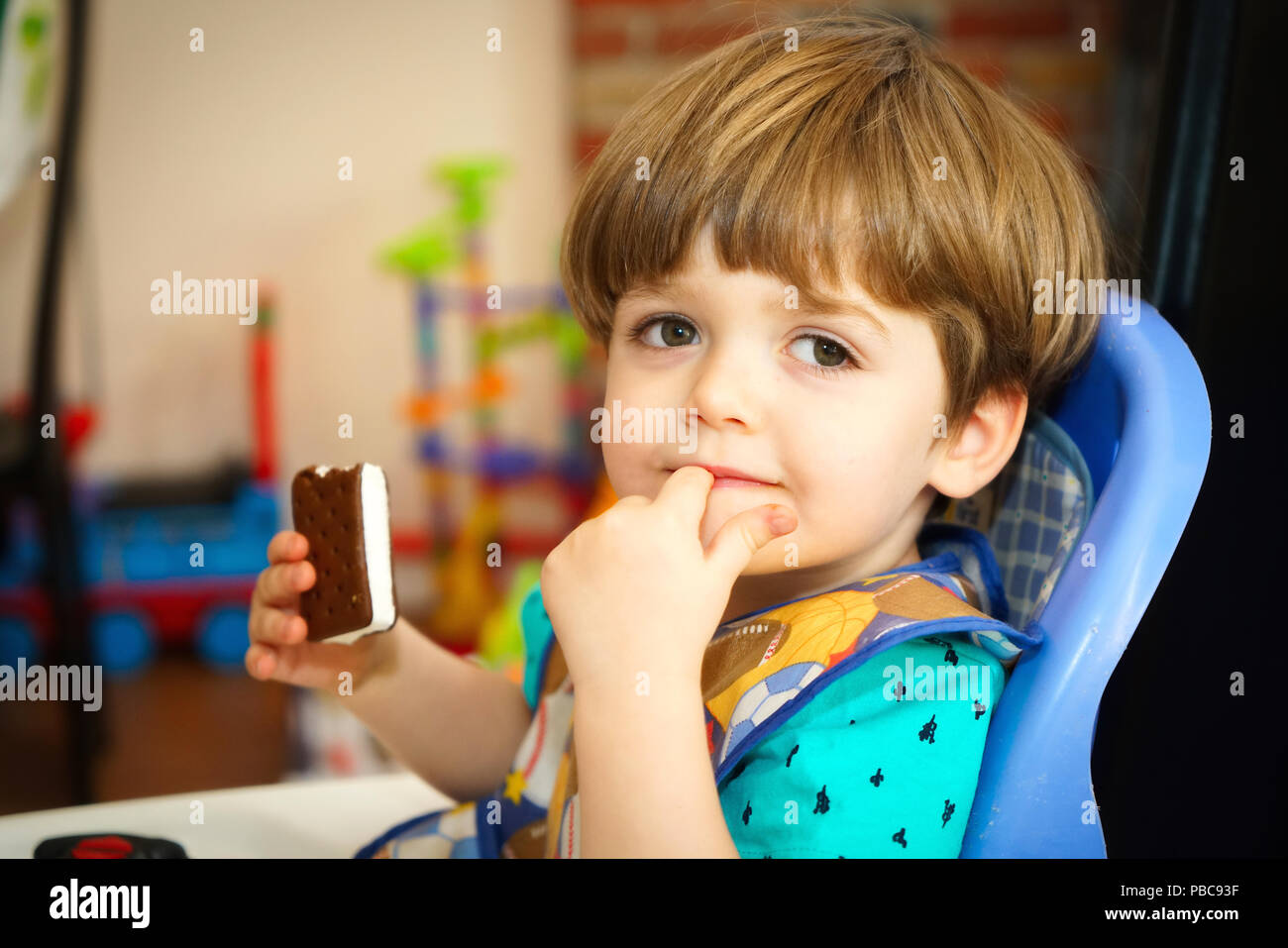 Montréal,Canada,21,juillet 2018.Jeune garçon manger un sandwich à la crème glacée dans une chaise haute.Credit:Mario Beauregard Banque D'Images