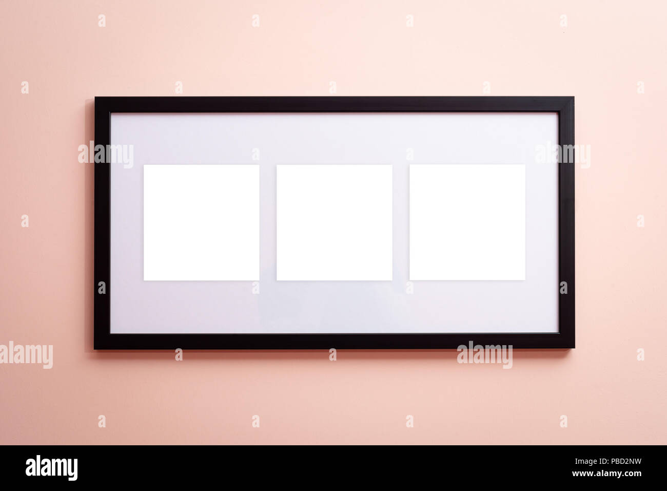 Une toile vierge black border frame avec trois espaces vides sur fond rose sur le mur Banque D'Images