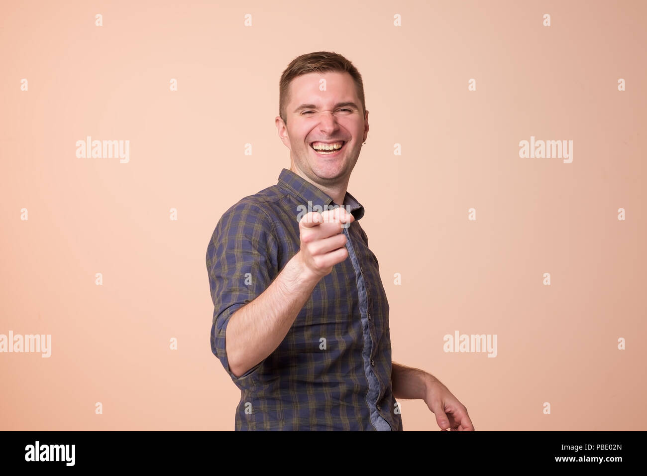 Portrait de jeune homme européen, rire, pointant du doigt avec quelqu'un. Banque D'Images