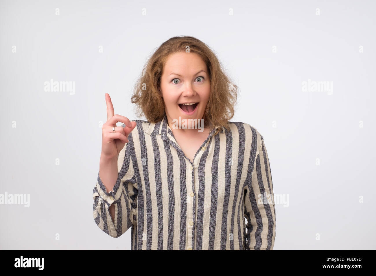 Photo de portrait of smiling lwoman isolé sur fond blanc pointant son doigt en signe d'eureka Banque D'Images