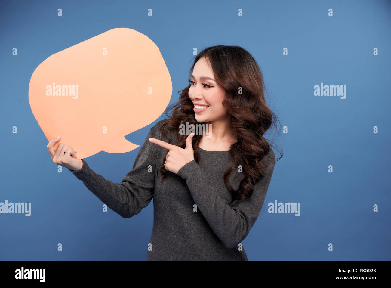 Belle jeune et jolie femme élégante et chic asiatique holding empty light brown bubble talk discours isolé sur fond bleu Banque D'Images