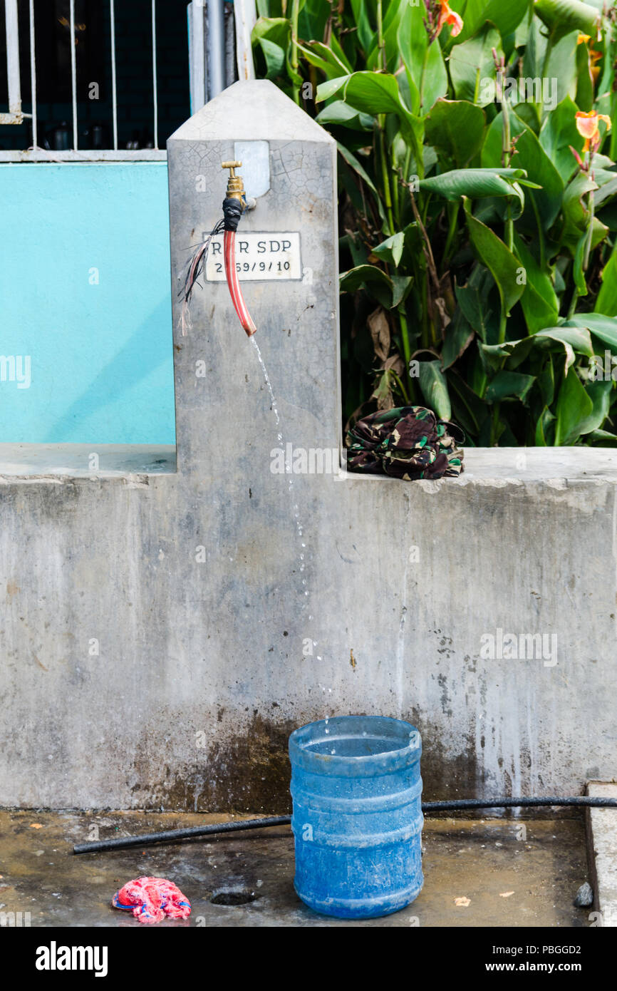Gouttes d'eau couler d'un robinet extérieur dans un pot d'eau dans les régions rurales du Népal Banque D'Images