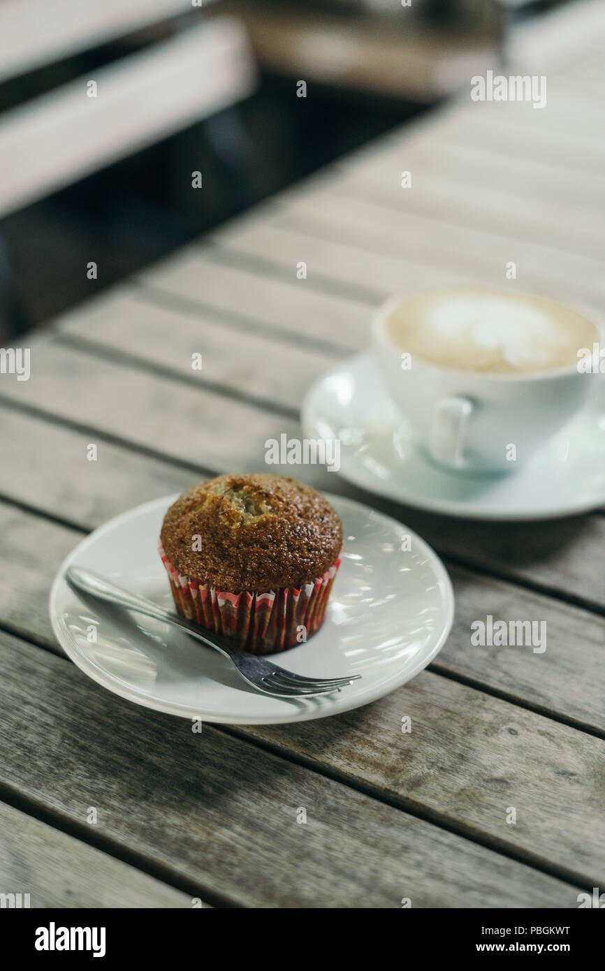 Cupcake banane avec du café chaud latte sur table en bois Banque D'Images
