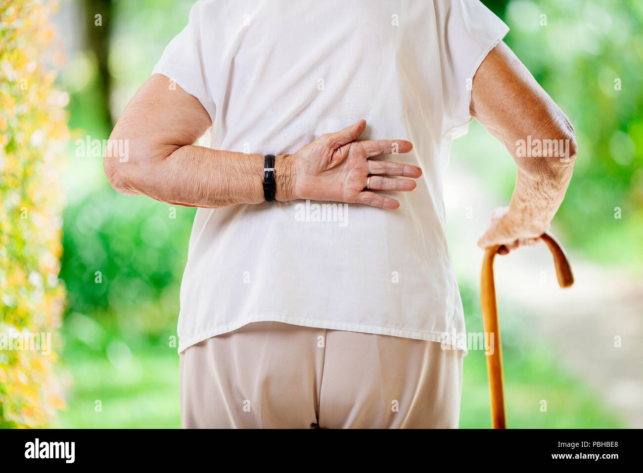 Femme âgée en plein air avec des douleurs au bas du dos Banque D'Images