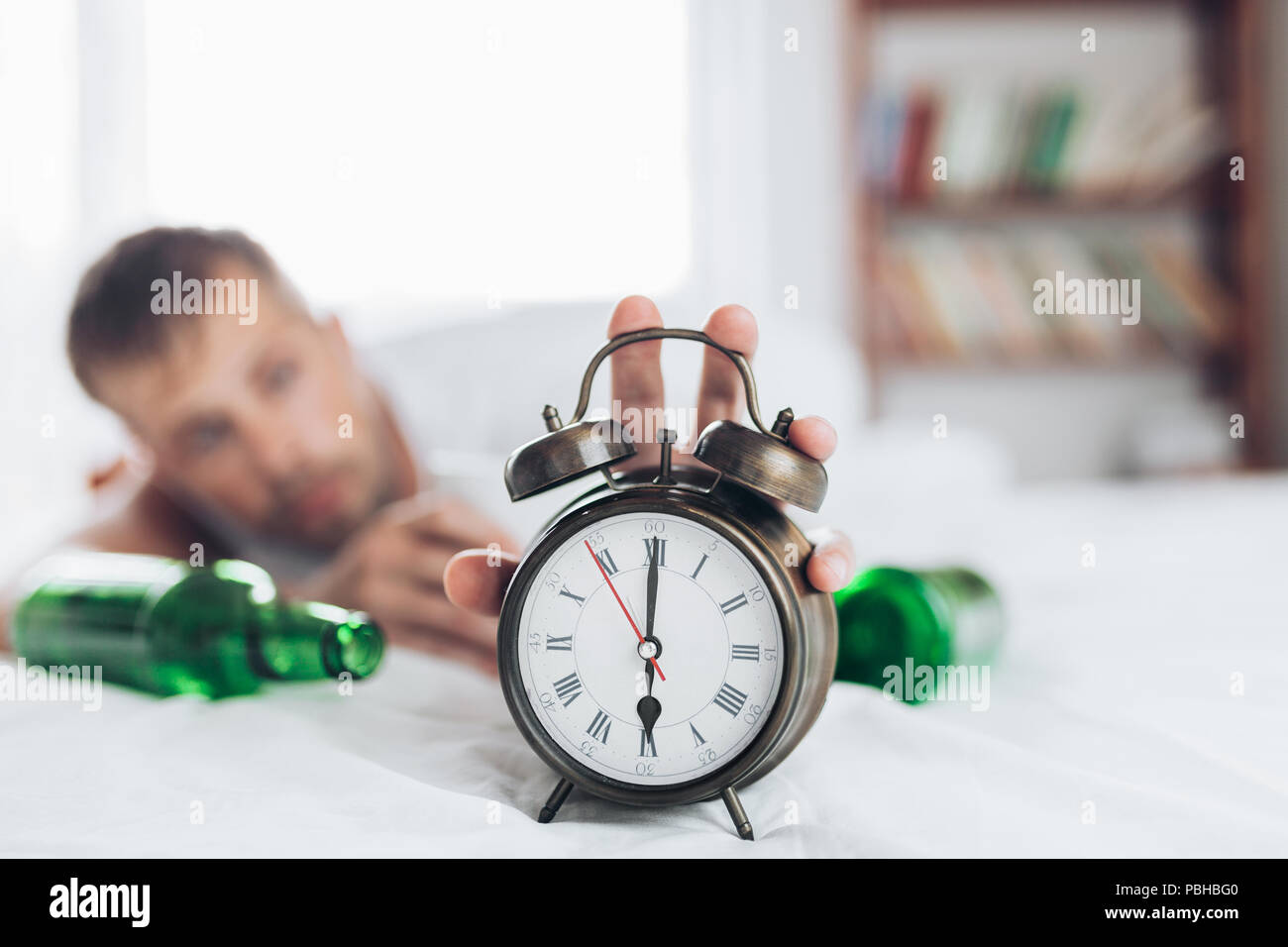 Jeune homme séduisant au lit le matin après nuit boire Banque D'Images