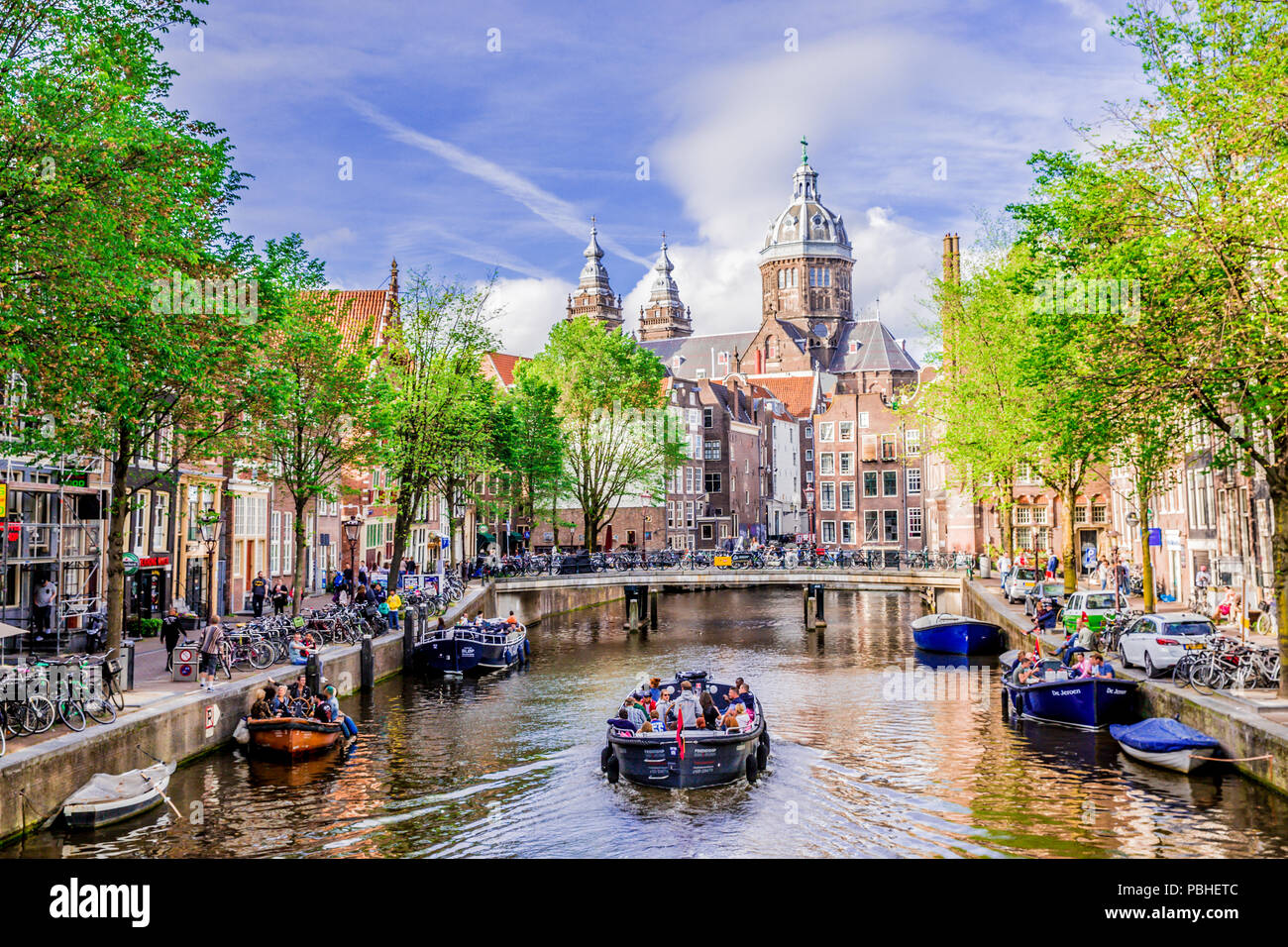 Bateau d'excursion au célèbre canal néerlandais sur une journée ensoleillée, entourée de vieux bâtiments traditionnels, dans la région de Red Light District, Amsterda, Pays-Bas. Banque D'Images