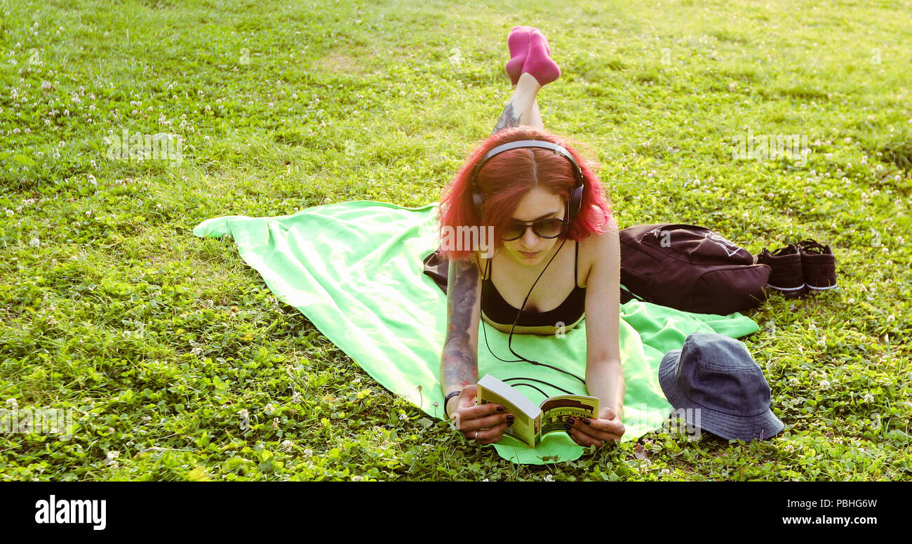 Girl Relaxing et lire un livre dans l'herbe du parc Banque D'Images