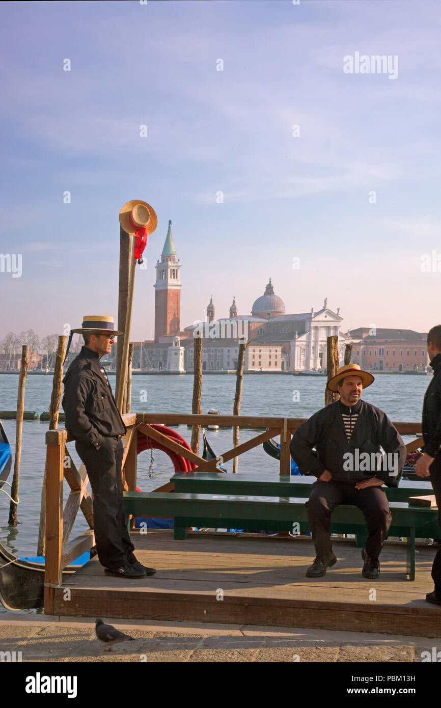 Gondoliers attendre un tarif sur le Molo, San Marco, avec la Chiesa di San Giorgio Maggiore en arrière-plan : Venise, Italie Banque D'Images