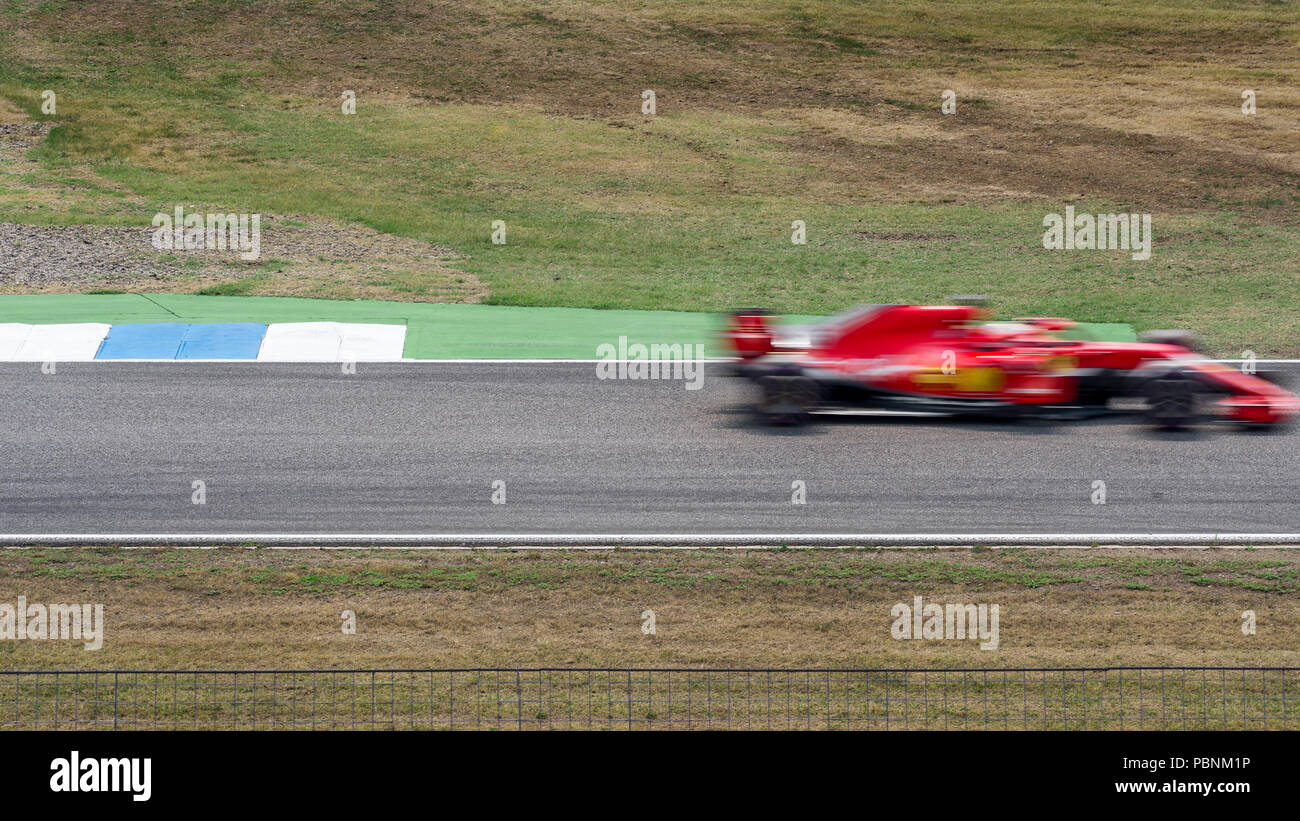 Une course de moto rouge en mouvement rapide voiture de sport monoplace passe devant le long de la piste de course dans un flou. Banque D'Images