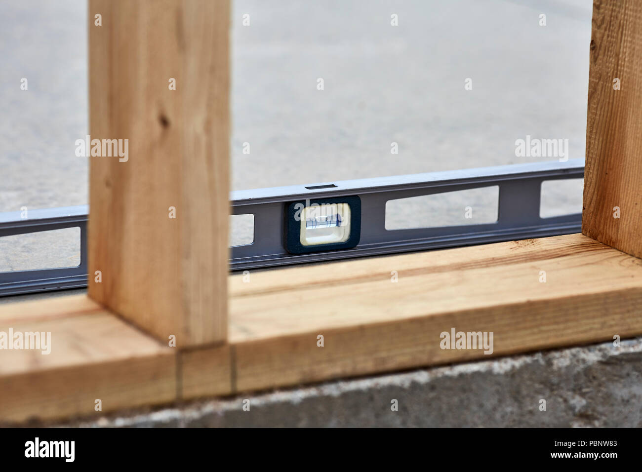 Niveau de charpentier portant sur une dalle de ciment à côté des poteaux en bois 2x4 sur un nouveau site de construction Banque D'Images