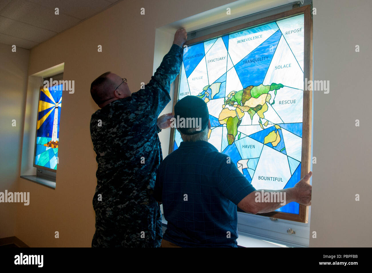 Naval Medical Center Portsmouth est un centre médical de la marine américaine situé à Portsmouth, en Virginie. Le 20 juillet 2018, le sixième vitrail a été installé dans sa chapelle dans le cadre du projet de rénovation de la Chapelle du confort. L'image d'archive documente le processus d'installation réalisé en coordination avec Shining Light vitrail de Poquoson, Virginie. Banque D'Images