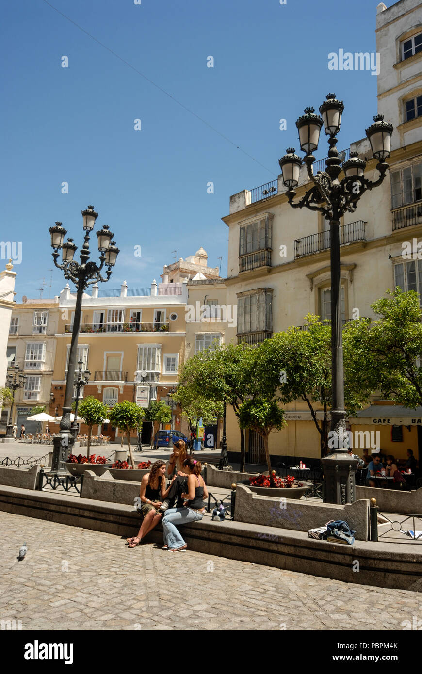 Les jeunes touristes assis sur l'épaulement sur la Plaza San Francisco dans la vieille ville de Cadix en Andalousie, Cadix la province, Espagne Banque D'Images