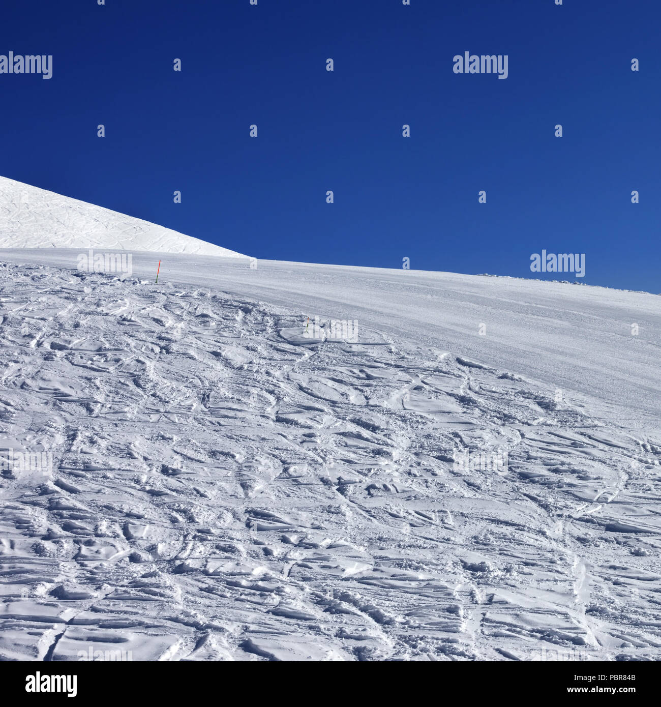 Pente enneigée avec trace de skis et snowboards et bleu ciel clair à Nice 24. La Géorgie, région Gudauri. Montagnes du Caucase à l'hiver. Banque D'Images