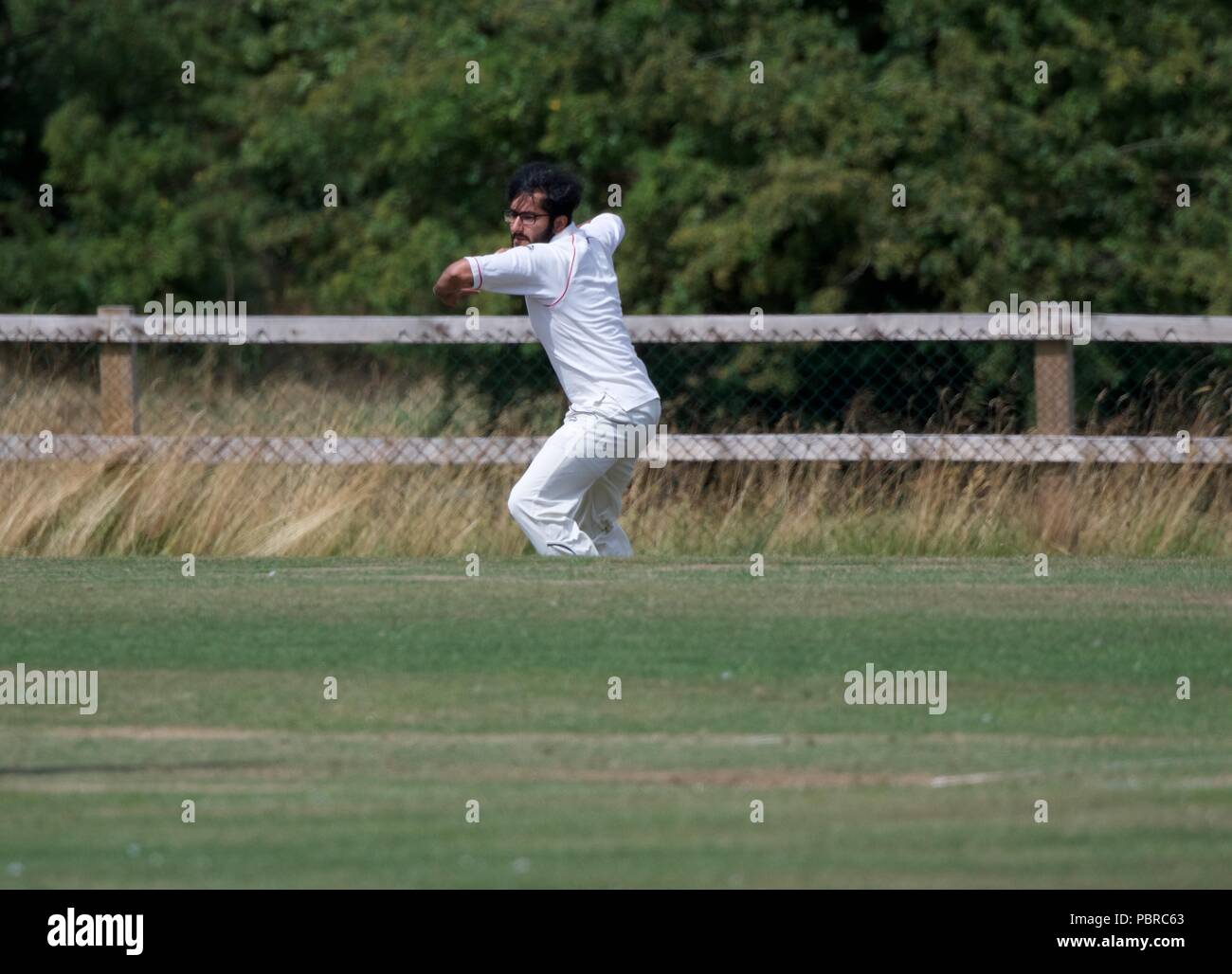 Un joueur lance la balle dans de la frontière dans un match de cricket entre Birch Vale et Thornsett deuxième équipe et Stalybridge St Paul's deuxième équipe. Banque D'Images