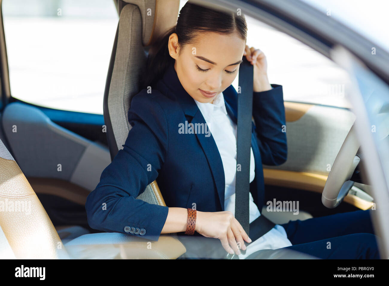 Belle femme sérieuse à la recherche à sa ceinture de sécurité Photo Stock -  Alamy