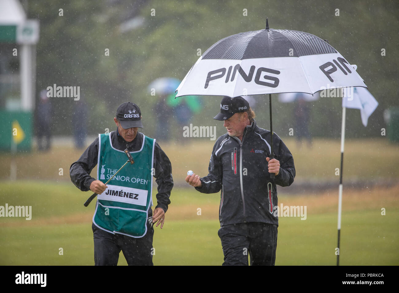 Miguel Angel Jimenez s'abrite de la pluie au 1er trou au cours de la quatrième journée de l'Open Senior au Old Course St Andrews. Banque D'Images