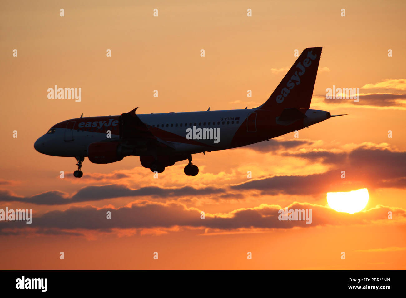 EasyJet airbus A319 avion G-EZDE se profile comme il passe devant le coucher de soleil tout en faisant son chemin dans d'atterrir à l'aéroport d'Édimbourg Banque D'Images