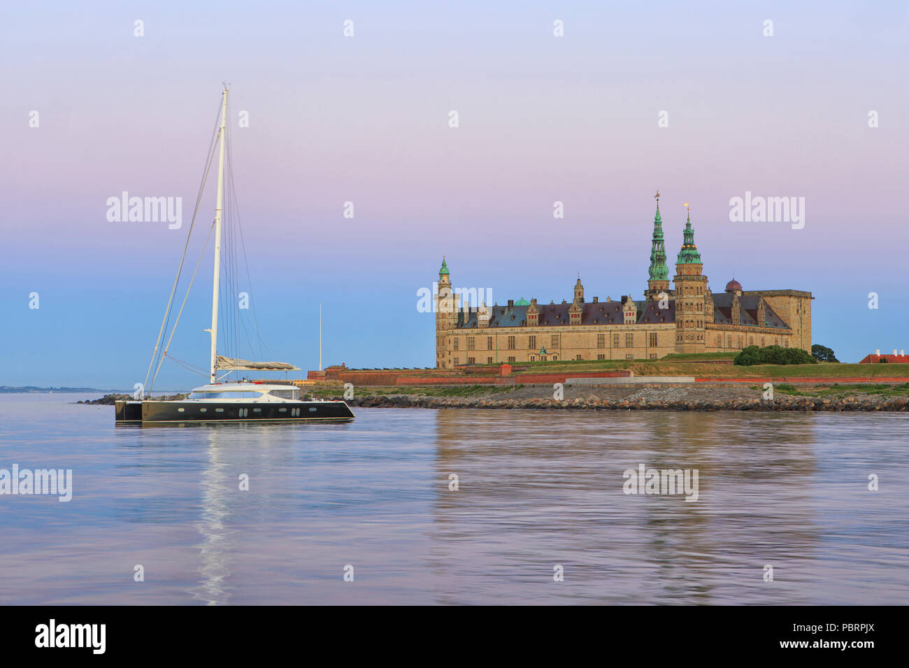 Un catamaran pour l'ancre à Château de Kronborg (Site du patrimoine mondial de l'UNESCO depuis 2000) au crépuscule dans Helsingor, Danemark Banque D'Images