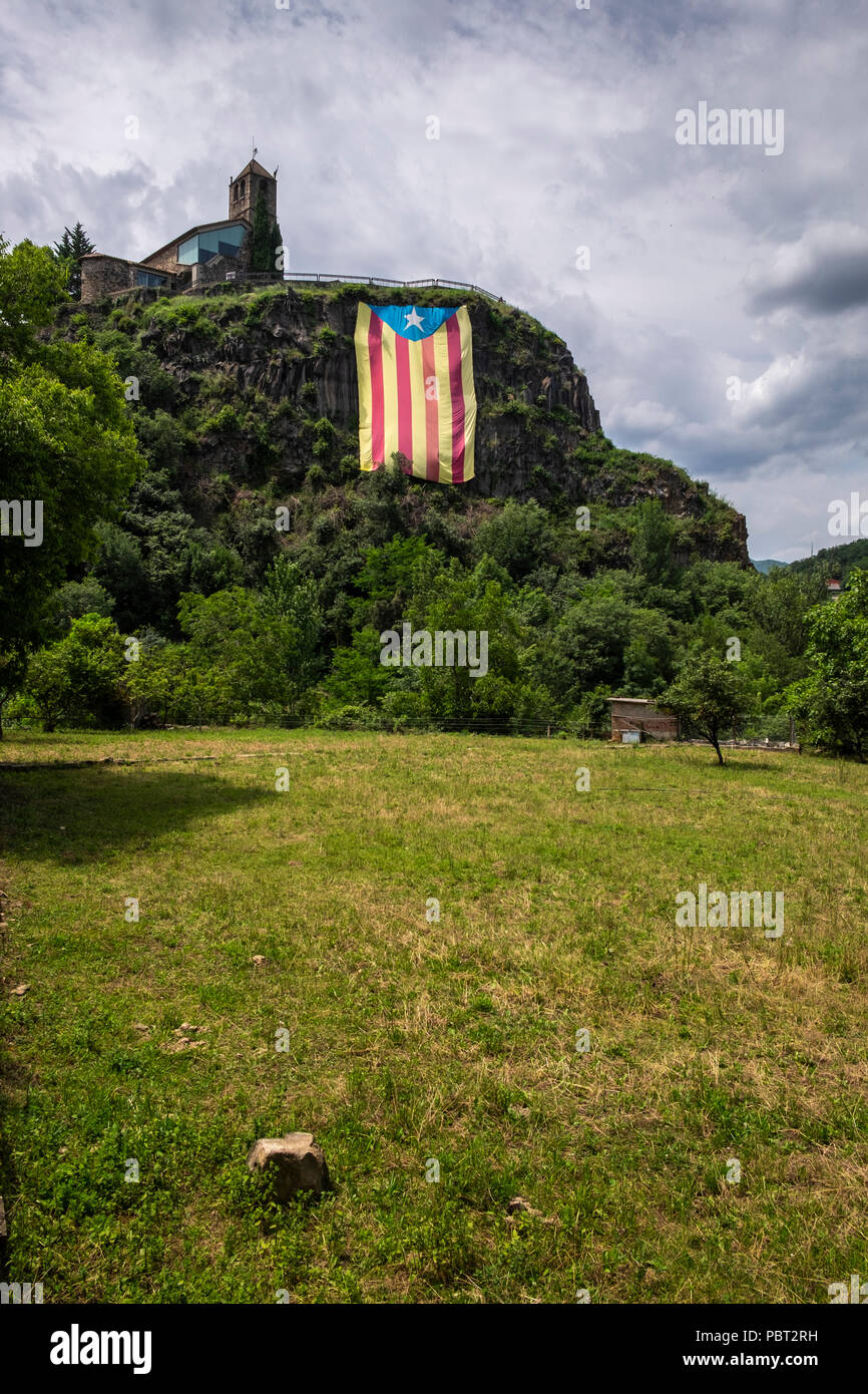 À la recherche jusqu'à Castellfollit de la Roca au sommet des hauteurs des falaises de basalte, escarpement rocheux, avec un énorme drapeau pendant vers le bas l'indépendance catalane Banque D'Images