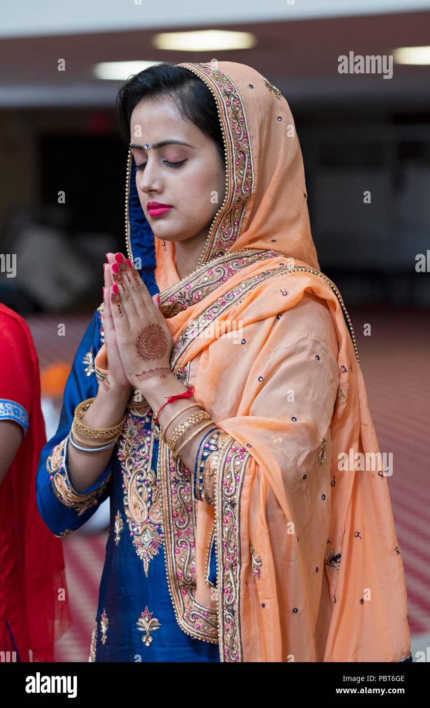 Un beau mariage guest prie et médite avant la cérémonie à un mariage sikh à Richmond Hill, Queens, New York. Banque D'Images