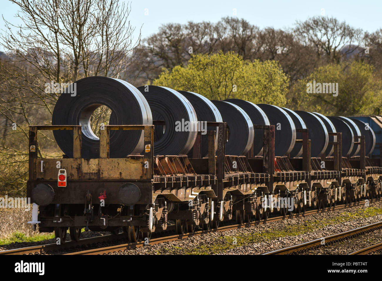 Le retour d'un long train de marchandises lourdes et de Camions plateaux de transporter de grosses bobines en acier d'une aciérie Banque D'Images