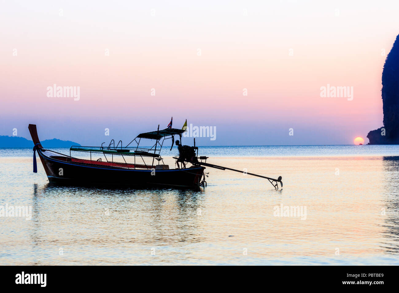 Silhouette of man sur bateau "long tail au coucher du soleil, Pak Meng, la province de Trang, Thaïlande Banque D'Images