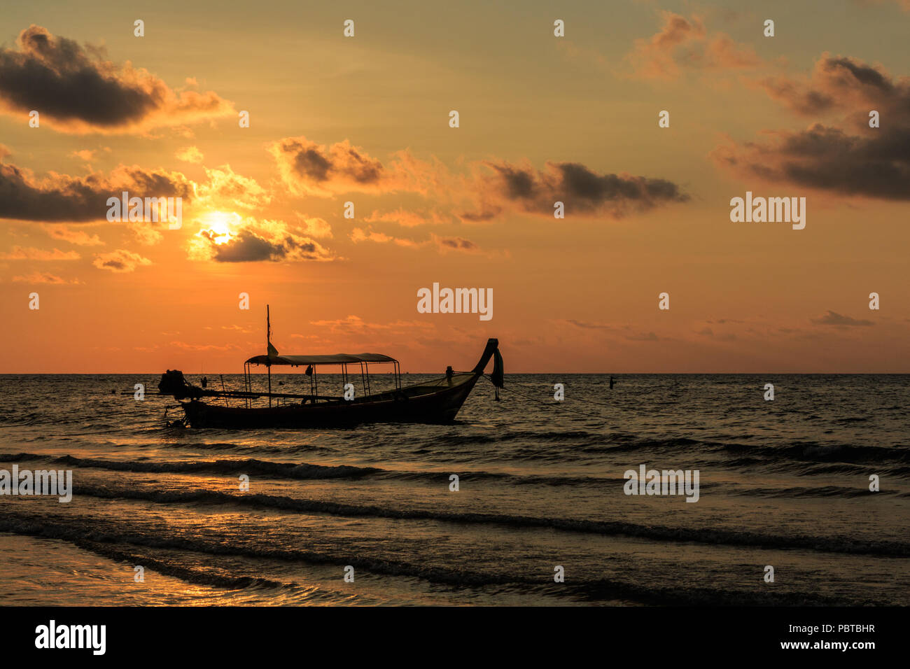 Bateau "long tail silhouetté contre le soleil tombant, Kamala Beach, Phuket, Thailand Banque D'Images