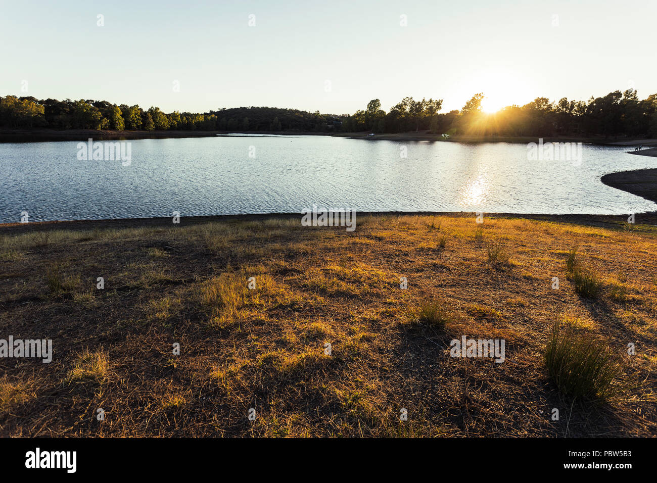 Bien au-dessus des arbres et leurs rayons se reflétant dans les eaux du lac et d'éclairage les herbes de la colline, Espagne Banque D'Images