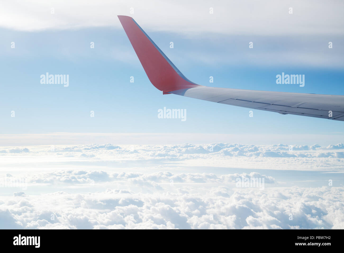 Vue aérienne de la fenêtre de l'avion sur les nuages et une aile d'avion dans le ciel bleu. Voler et voyager concept. Banque D'Images