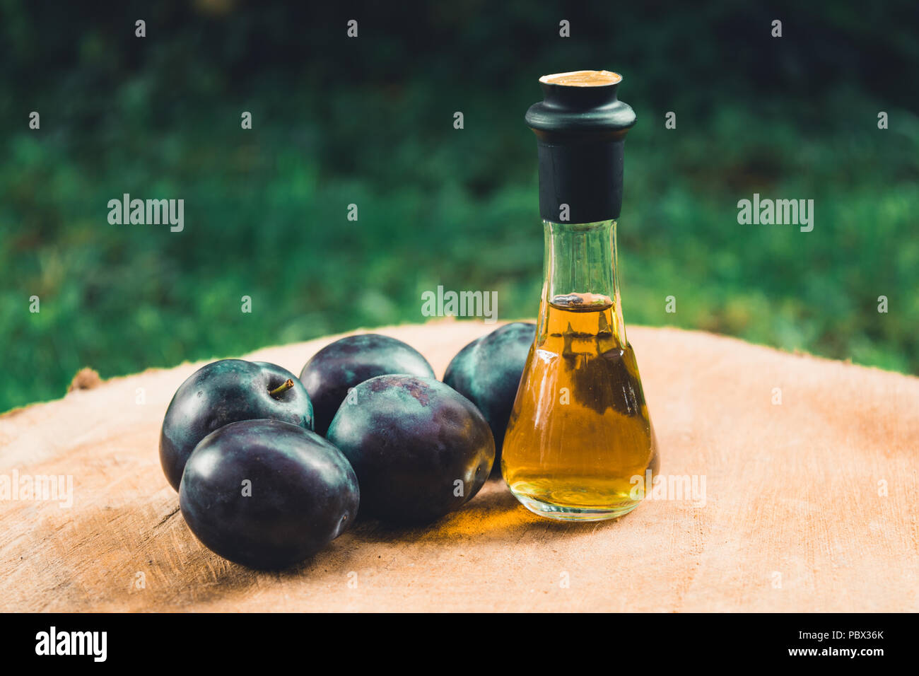 Eau-de-vie de prune (Slivovitz) en serbe traditionnel verre bouteille avec les prunes mûres fraîches sur une surface en bois. Banque D'Images