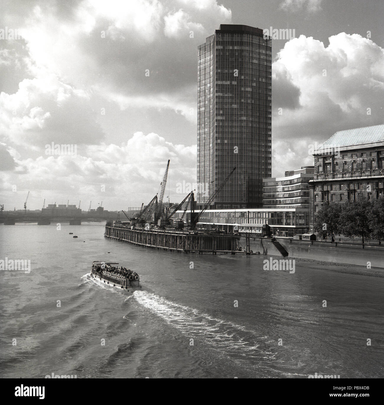 Années 1960, historique, un bateau de plaisance s'abaisse, la Tamise à la Cleveland bridge landing stage ou plate-forme flottante, à côté d'un moderne récemment construit des tours d'immeuble de bureaux à Londres, Angleterre, Royaume-Uni. Les années 60 ont vu les bords de la Tamise changer à jamais les quais ont été développés dans des blocs de la tour et de l'habitation. Banque D'Images