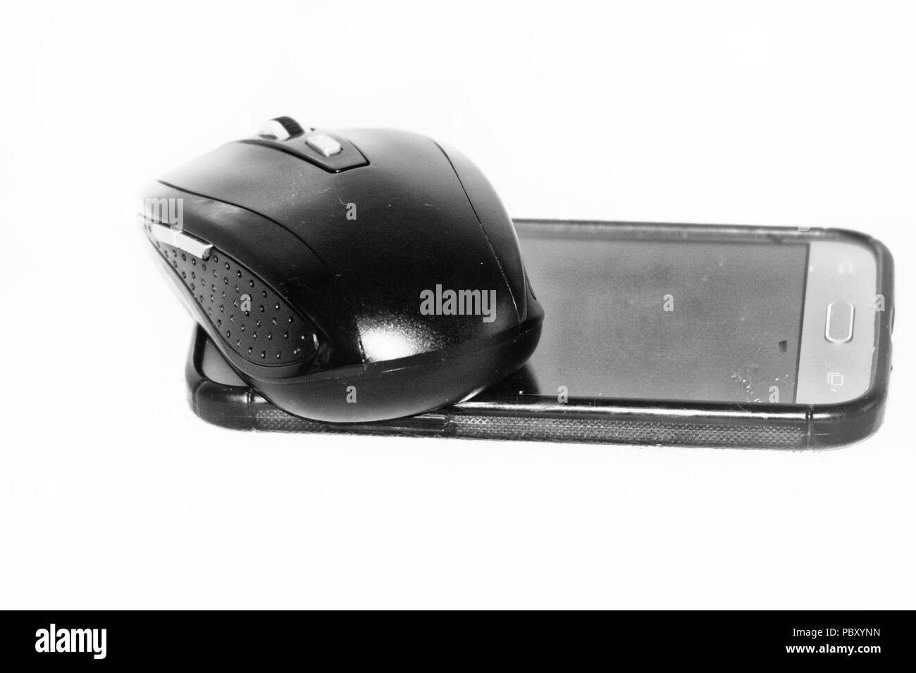 Une souris sans fil au-dessus d'un téléphone mobile sur un fond blanc Banque D'Images