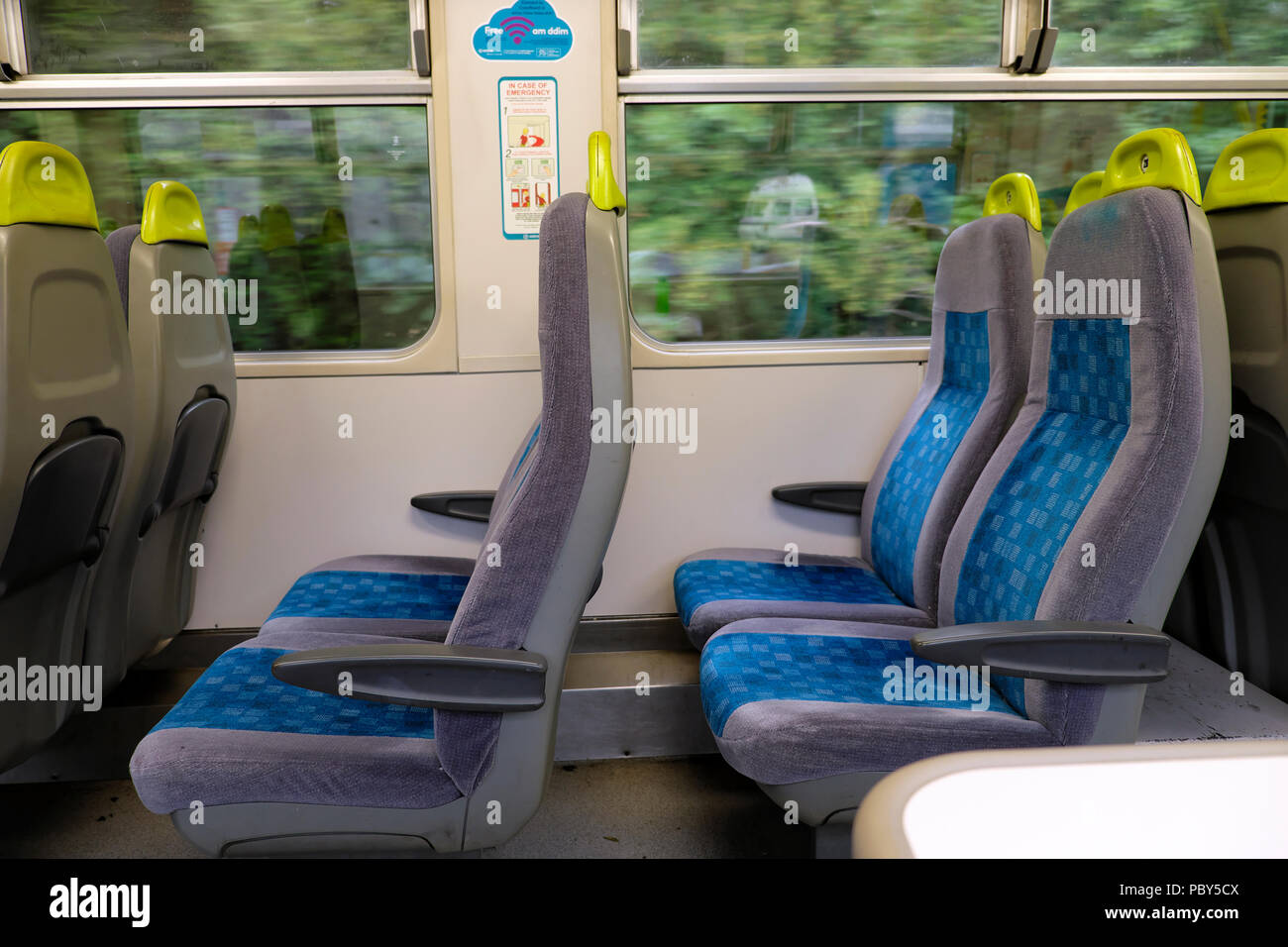Intérieur D'UN WAGON DE TRAIN ARRIVA Rembourrés Sièges BLEU VIDE MONTRANT ET VUE DE L'excès de feuillage à l'extérieur du pays de Galles UK WINDOWS KATHY DEWITT Banque D'Images