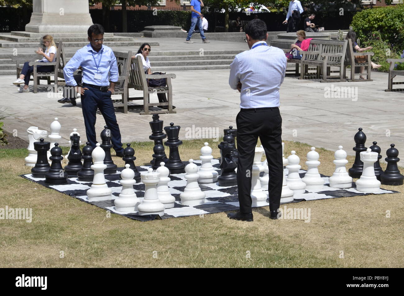 Deux hommes d'affaires asiatiques jouant aux échecs en plein air sur leur pause déjeuner dans la région de Grosvenor Square, Mayfair, Londres Banque D'Images