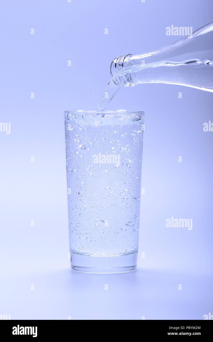 Un grand verre d'eau minérale rafraîchissante versé d'une bouteille Banque D'Images