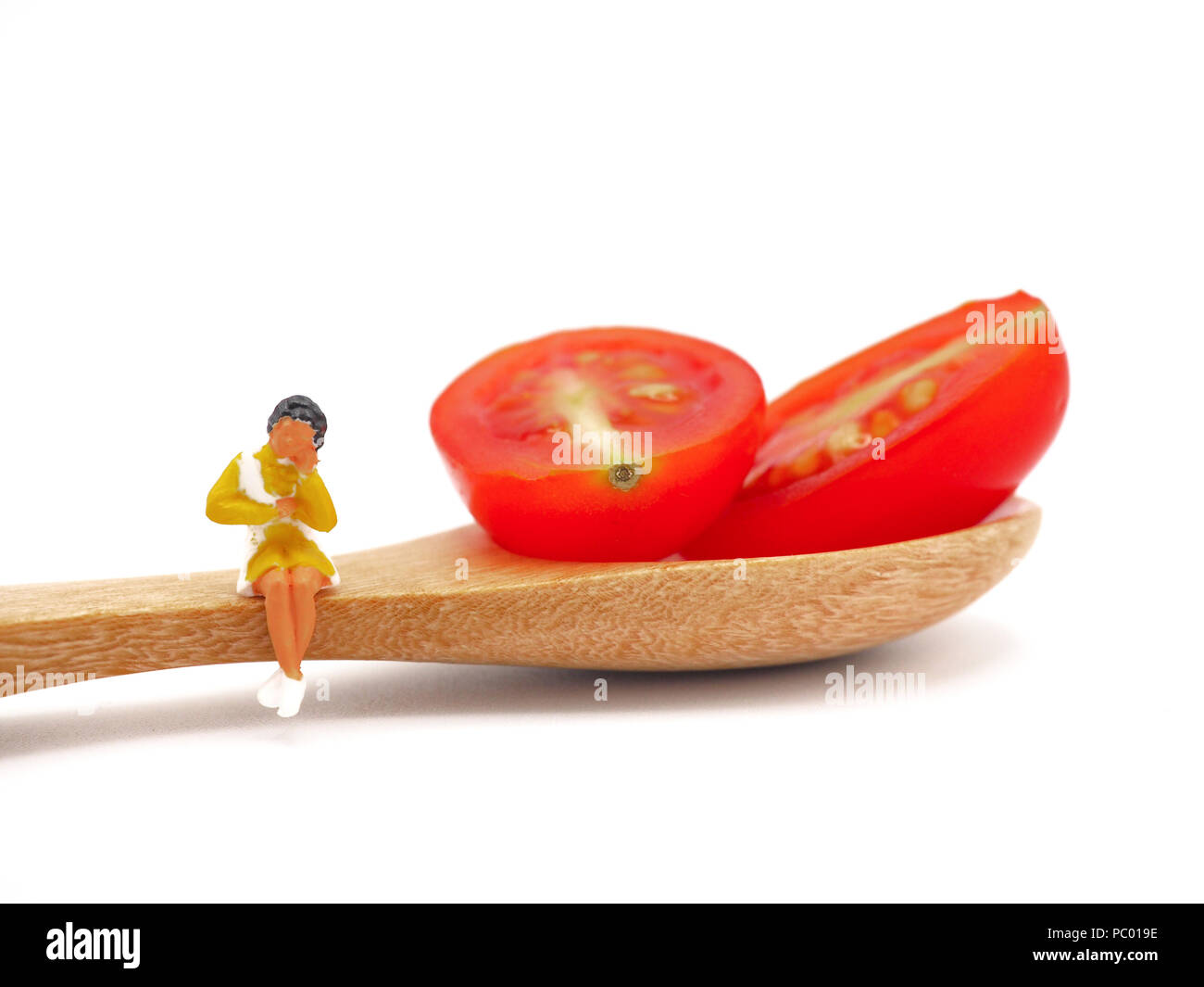 Femme assise sur miniature ou de raisin frais tomate cerise avec une cuillère de bois, la pensée de la perte de poids et de corps mince. Concept de vie sain bac blanc. Banque D'Images