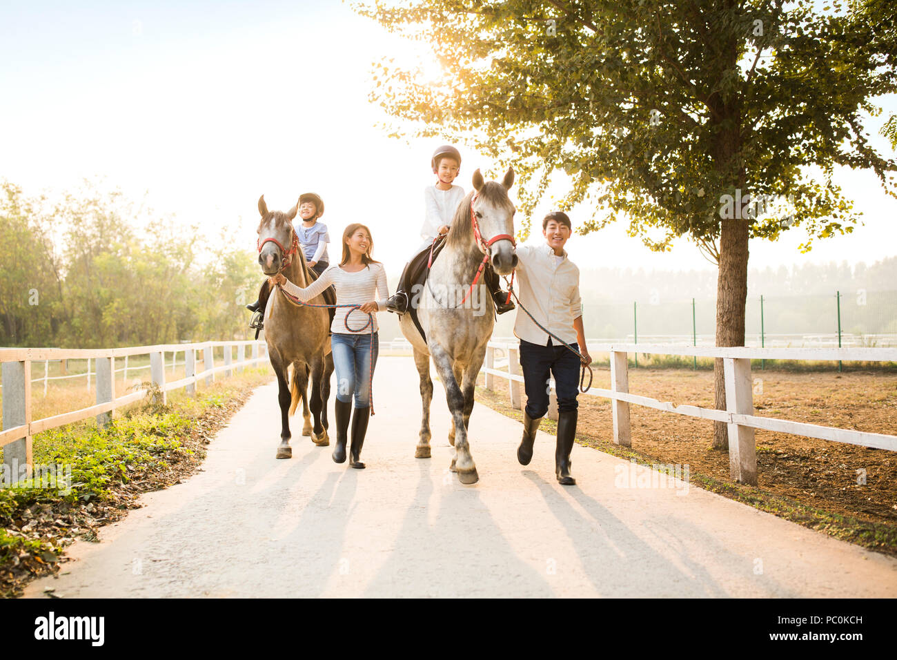 Cheerful young Chinese family riding horses Banque D'Images