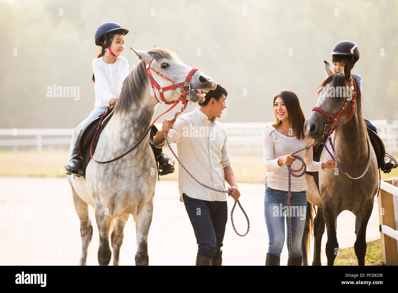 Cheerful young Chinese family riding horses Banque D'Images