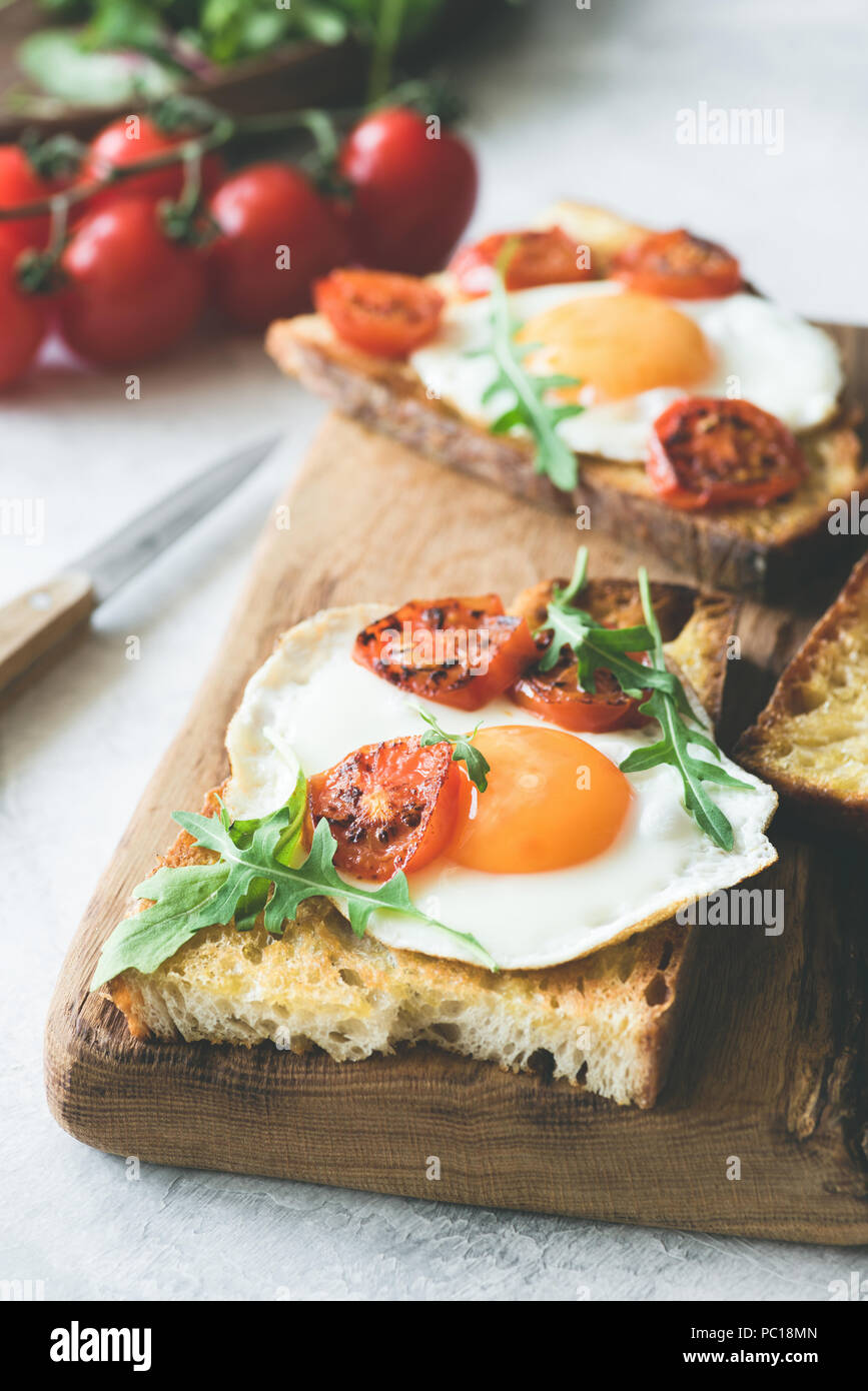 Sandwich de petit-déjeuner avec des œufs, du fromage et des tomates sur une planche à découper en bois rustique. Vue rapprochée, selective focus. Image tonique Banque D'Images