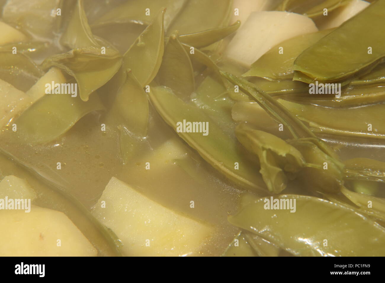 Les gousses de pois et de pommes de terre dans la soupe Banque D'Images