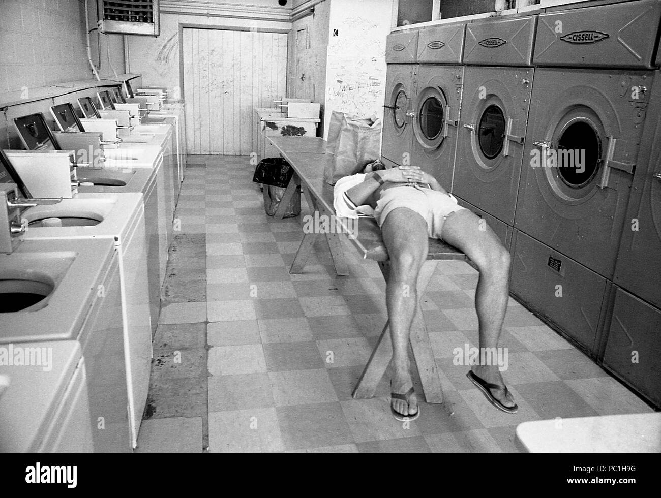 L'homme de prendre une sieste en attendant dans une laverie automatique. Ancien lavoir, U.S.A., 1982 Banque D'Images