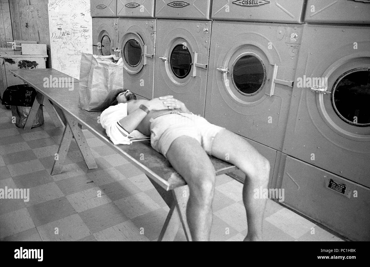 L'homme de prendre une sieste en attendant dans une laverie automatique. Ancien lavoir, U.S.A., 1982 Banque D'Images