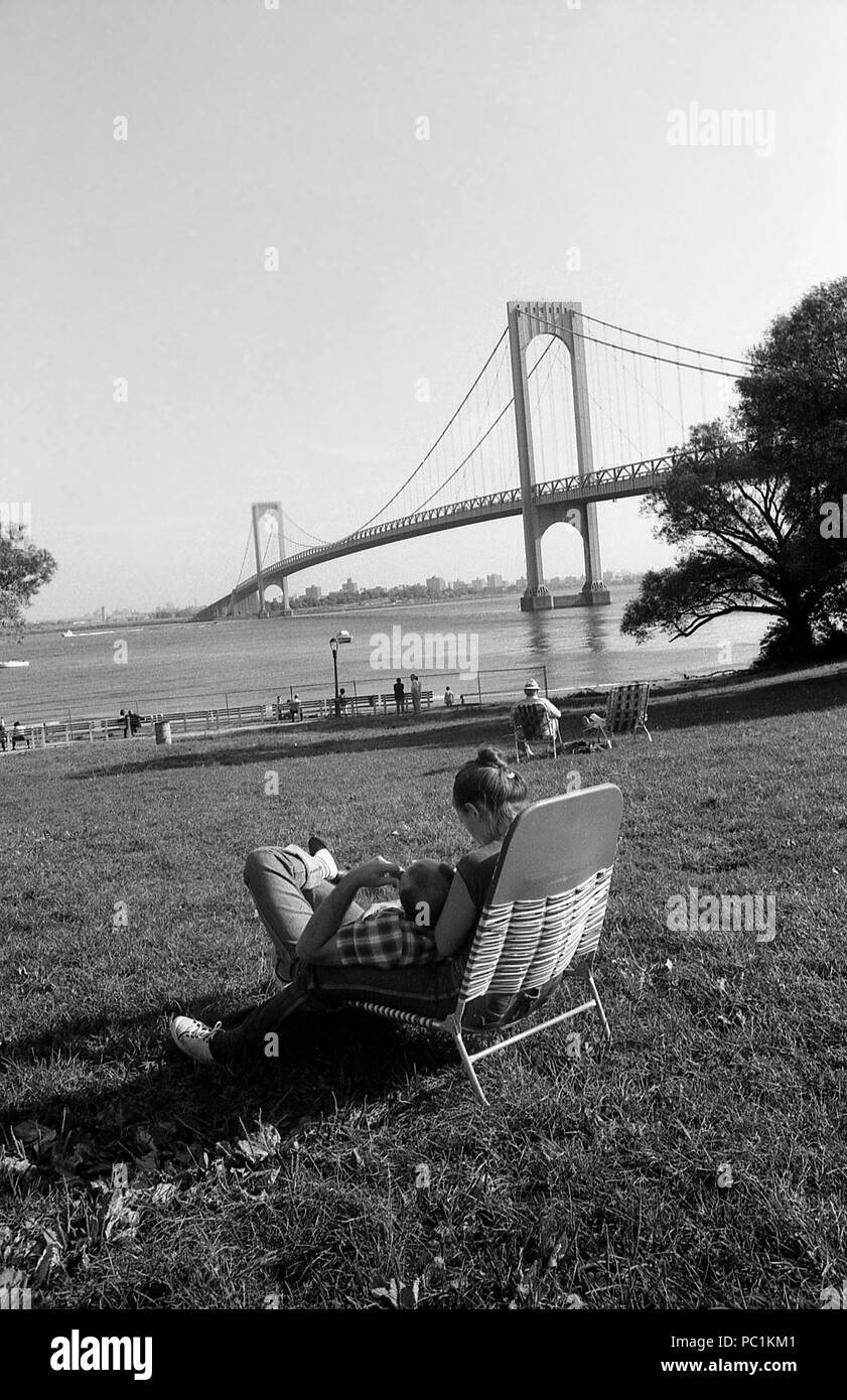 New York City, NY, États-Unis, 1982. Les gens se détendent dans le parc près de la rivière Hudson, New York. Bronx- Whitestone Bridge reliant le Bronx au Queens à New York. Banque D'Images