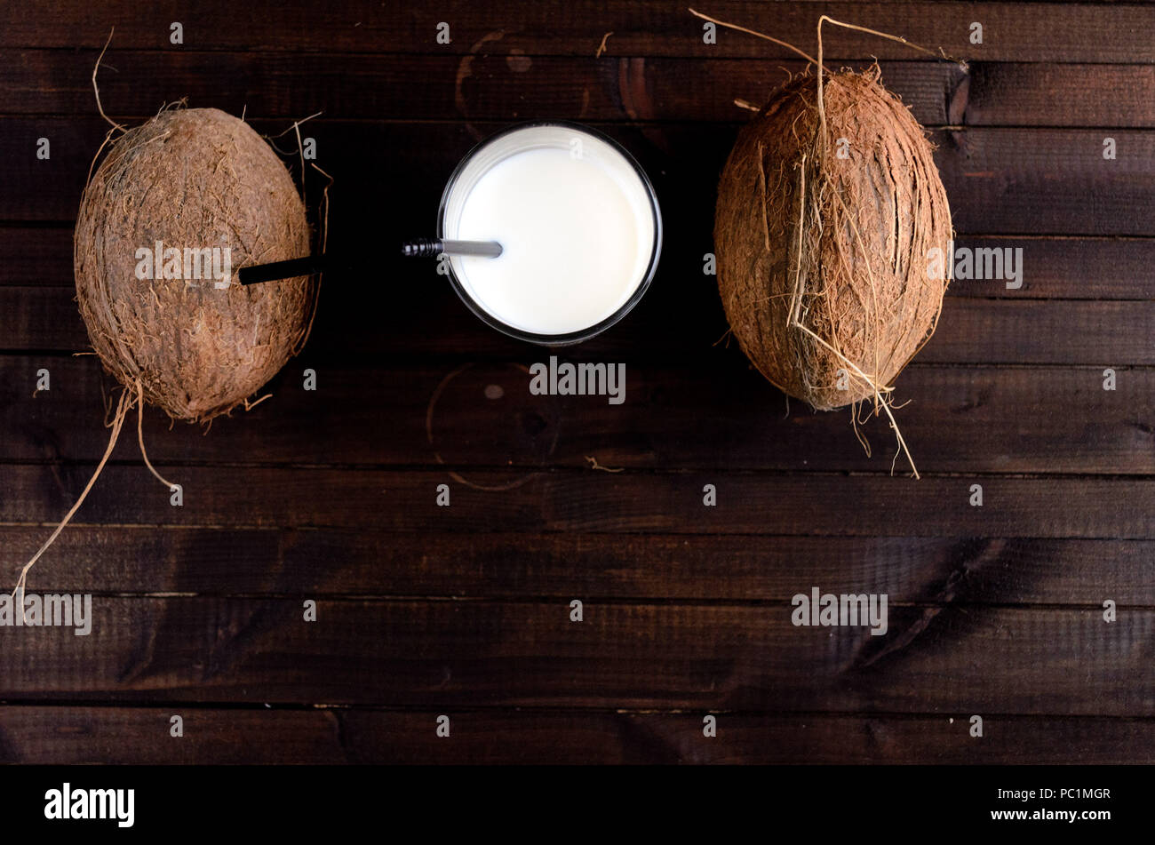 Un verre de lait de coco et deux cocotiers sur fond de bois.Copyspace down.Flatlay point de vue. Banque D'Images