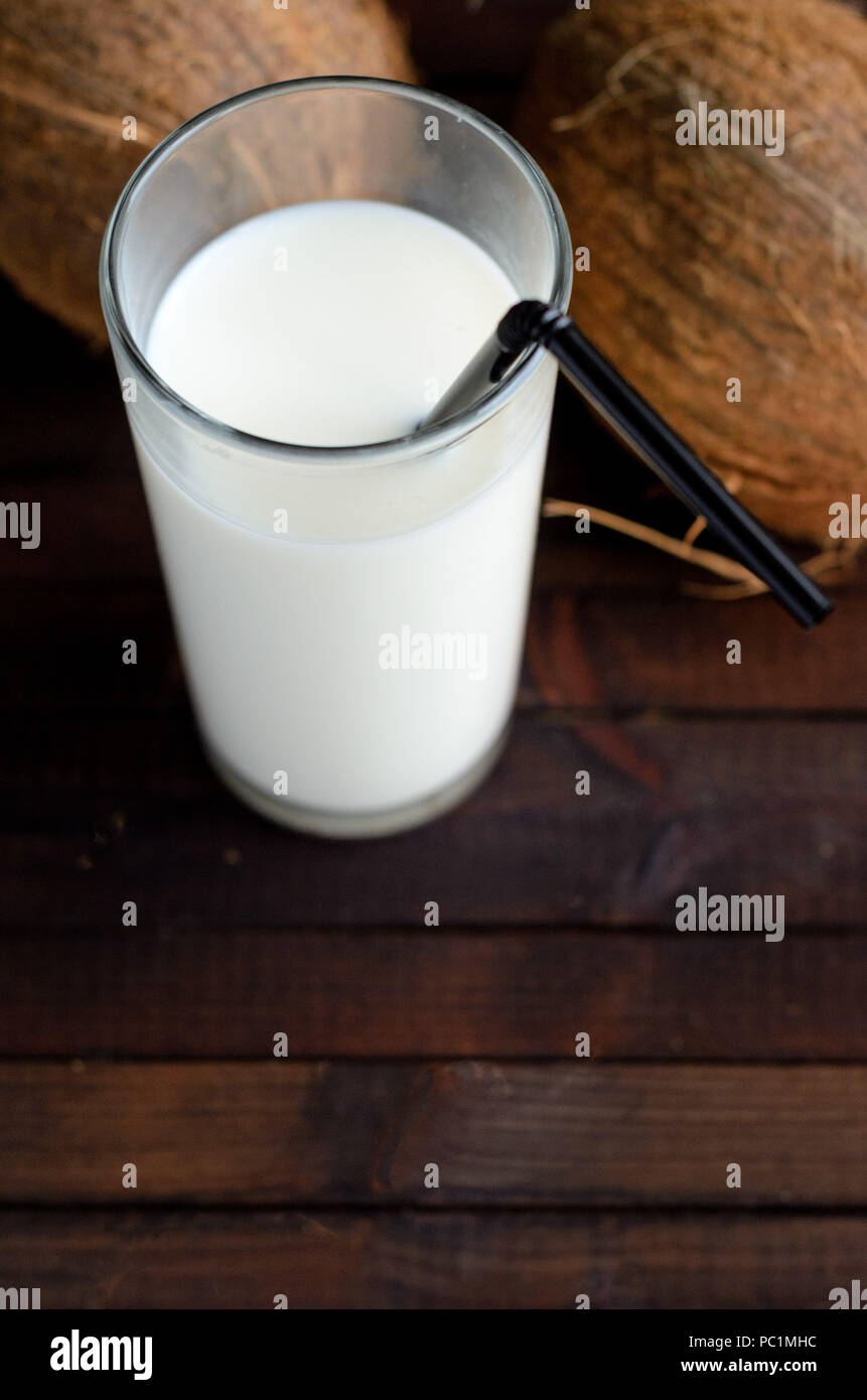 Un verre de lait de coco et deux cocotiers sur fond de bois.Copyspace vers le bas. Banque D'Images