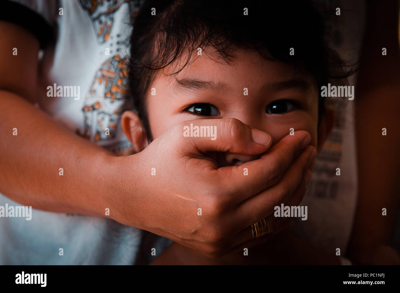 Image conceptuelle des abus envers les enfants avec des mains adultes couvrant la bouche de la jeune fille. Banque D'Images