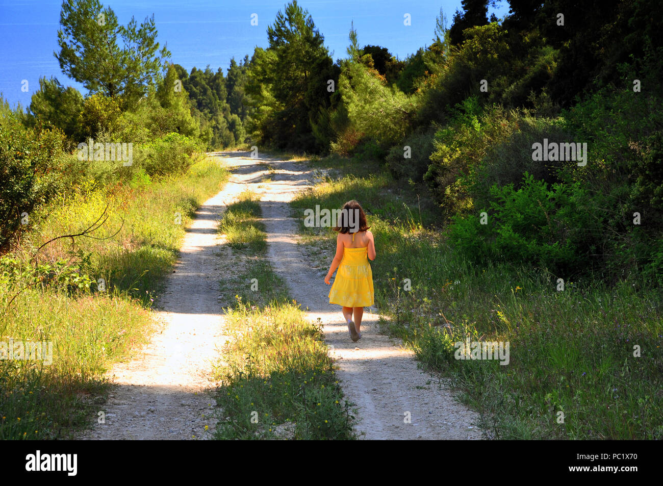 Petite fille en robe jaune marchant sur le chemin Banque de