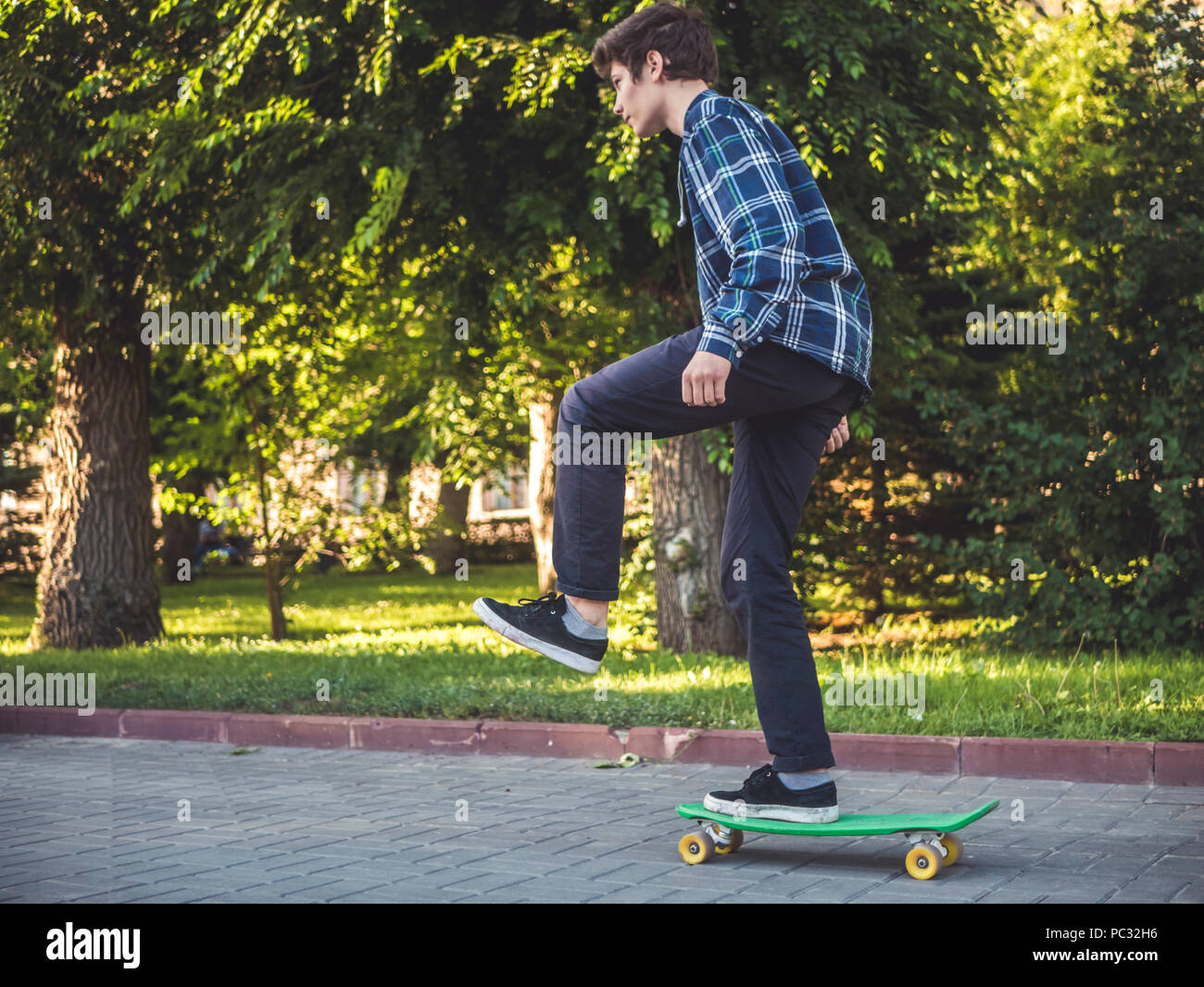Jeune hipster riding a penny board skateboard dans la rue de la ville d'été Banque D'Images